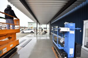 青い外壁の建物に設置された大きな雨よけの屋根(キャノピー)とエアダスター