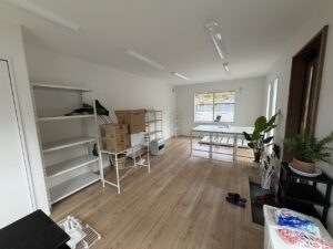 窓際に配置された白いデスクと収納棚のあるオフィスのレイアウト