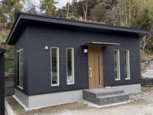 黒い外壁と木目調ドアがスタイリッシュな株式会社みやび緑地の平屋オフィス外観